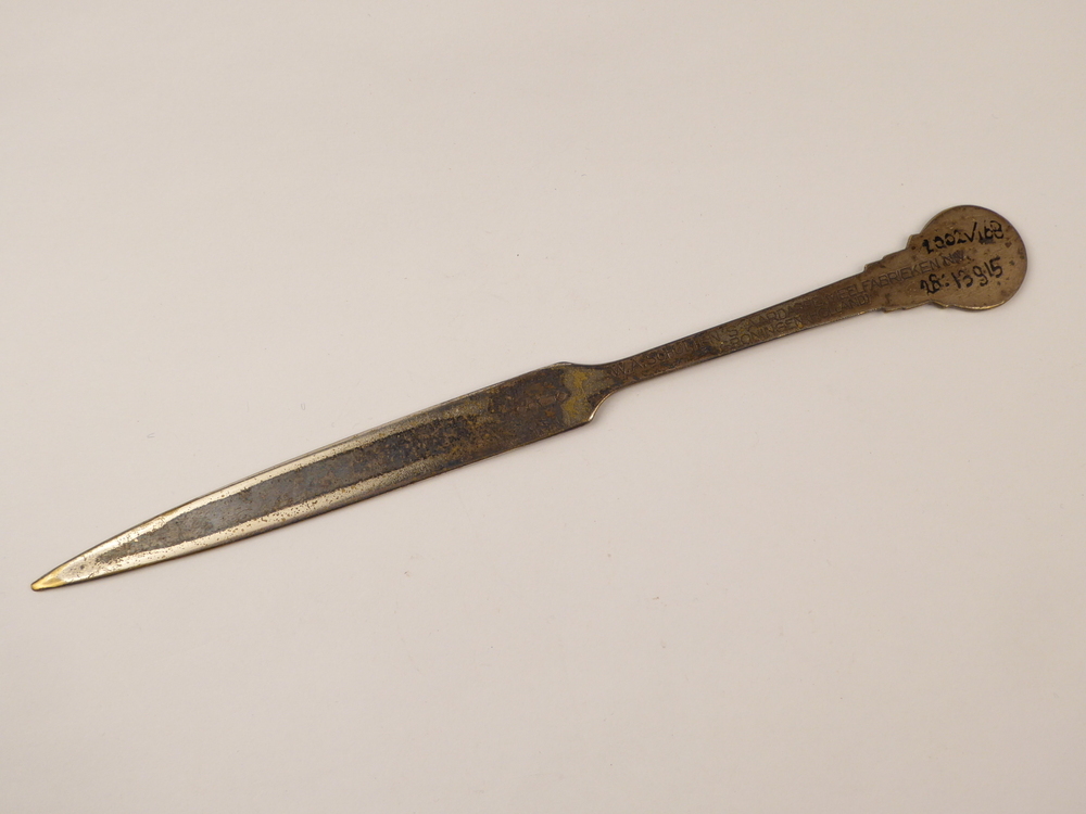 langwerpige spitse verzilverde messingen briefopener met op uiteinde decoratie S in ster, aan achterzijde gegraveerd W.A.Scholten's aardappelmeelfabrieken Groningen (Holland)