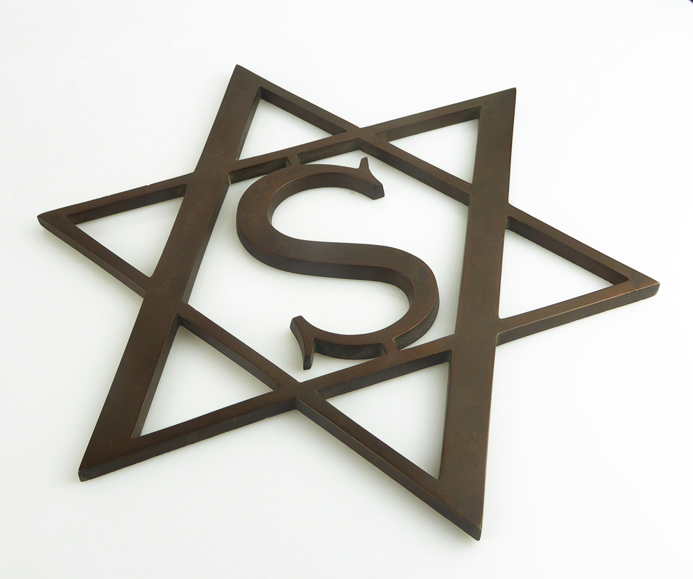 rood koperen vignet logo van het W.A.Scholten concern, voorstellende een dubbele driehoek met daarin de letter S. Afkomstig uit nalatenschap van Alfred Hooglander (1934-2007), werkte vanaf eind jaren 50 tot aan de overname / sluiting bij Scholten