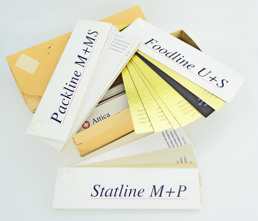 gelige kartonnen doos met hierin 6 stalenkaarten van kartonfabriek Attica BV te Oude Pekela, respectievelijk met opdruk Packline M+MS, Luxline, Statline M+P, Induline M+P, Foodline U+S en Printline.