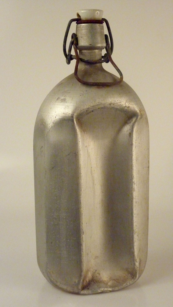 achthoekige tinnen fles met sluiting van metaal en porselein en op dop opdruk in blauw Markill