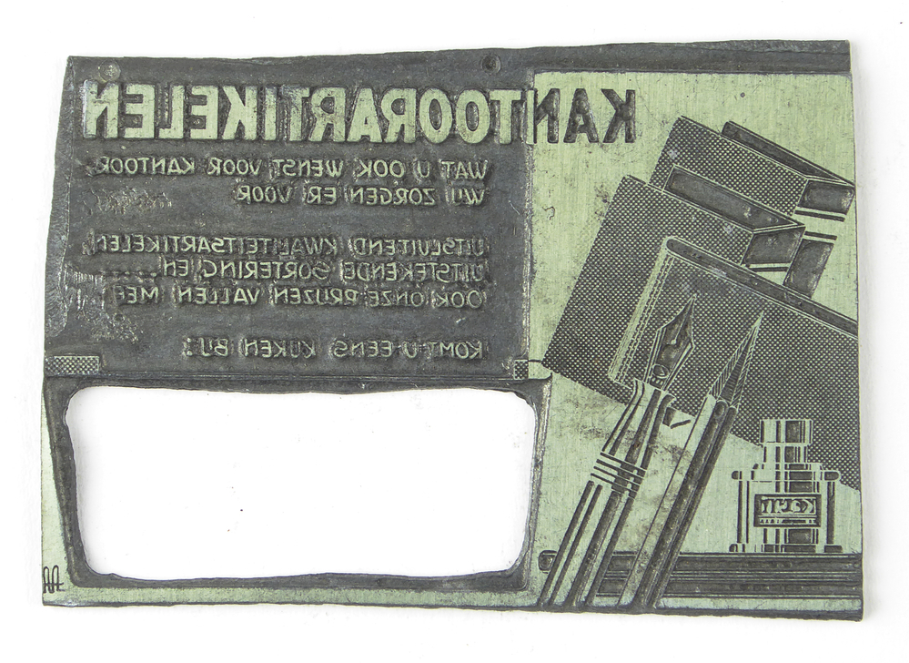 rechthoekige non ferro metalen cliche met overdwars een gat en afbeelding kroontjespen, inktpot en cahiers en inscriptie kantoorartikelen wat u ook wenst voor kantoor wij zorgen ervoor uitsluitend kwaliteitsartikelen uitstekende sortering en.... ook onze prijzen vallen mee komt u eens kijken bij, op achterkant oranje sticker met zwarte opdruk boek- en kantoorboekhandel Schuur Veendam, afkomstig van kantoorinstallaties Bv Schuur te Veendam