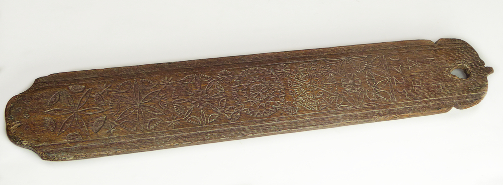 rechthoekige lange houten plank met afgeronde boven en onderkant, bovenin hartvormig gat, aan voorkant gekerfde belettering H F A I en 1725, daaronder 7 x ingekerfde bloemdecoraties