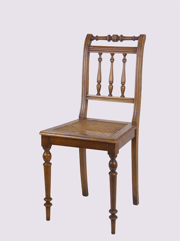 Houten stoel met aan voorkant ronde gedraaide poten, aan achterkant ietwat gebogen rechthoekige poten, gevlochten rieten / rotan zitting, ietwat gebogen rugleuning met 3 verticale ronde gedraaide spijlen, bovenaan horizontaal geplaatste ronde gedraaide houten dwarsbalk.