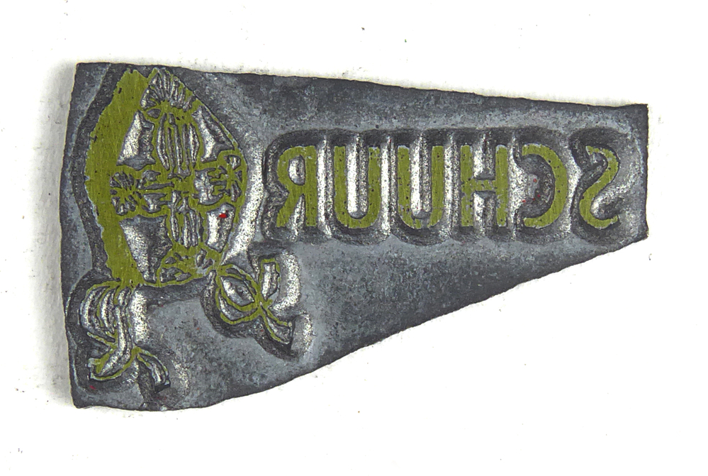 kleine iets scheve non ferro metalen cliche met afbeelding mijter en inscriptie Schuur, afkomstig van kantoorinstallaties Bv Schuur te Veendam