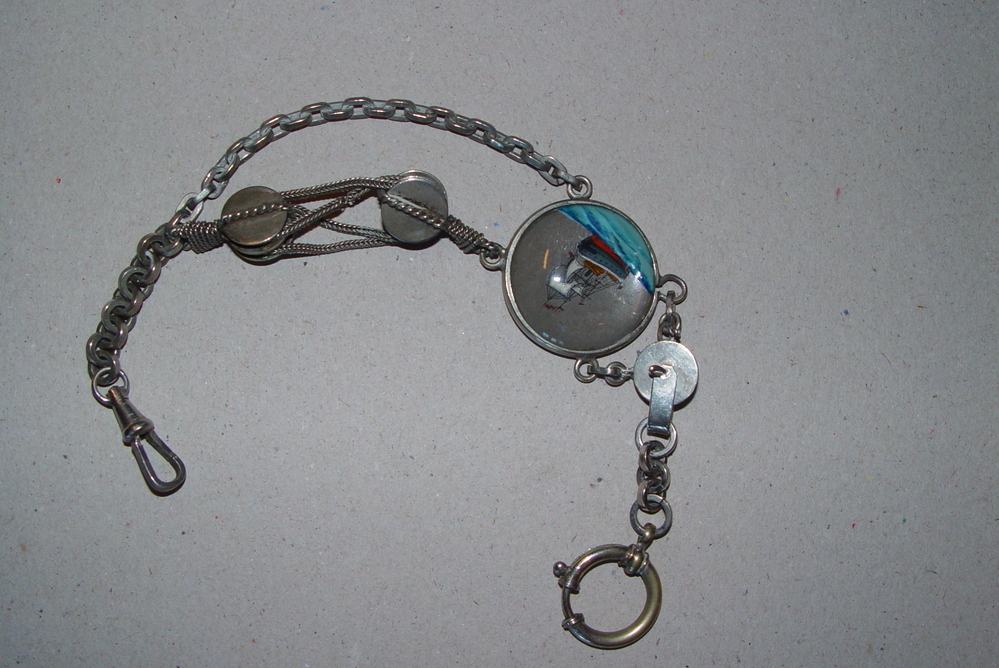 Medaillon / horlogeketting ongeveer 1825 (inv.boek) in de vorm van 2 dubbelblokken met touw waaraan een medaillon hangt met afbeelding van een zeilschip, keerzijde stervormig geometrisch motief, afkomstig van Lucas Warntjes, stuurman uit Muntendam